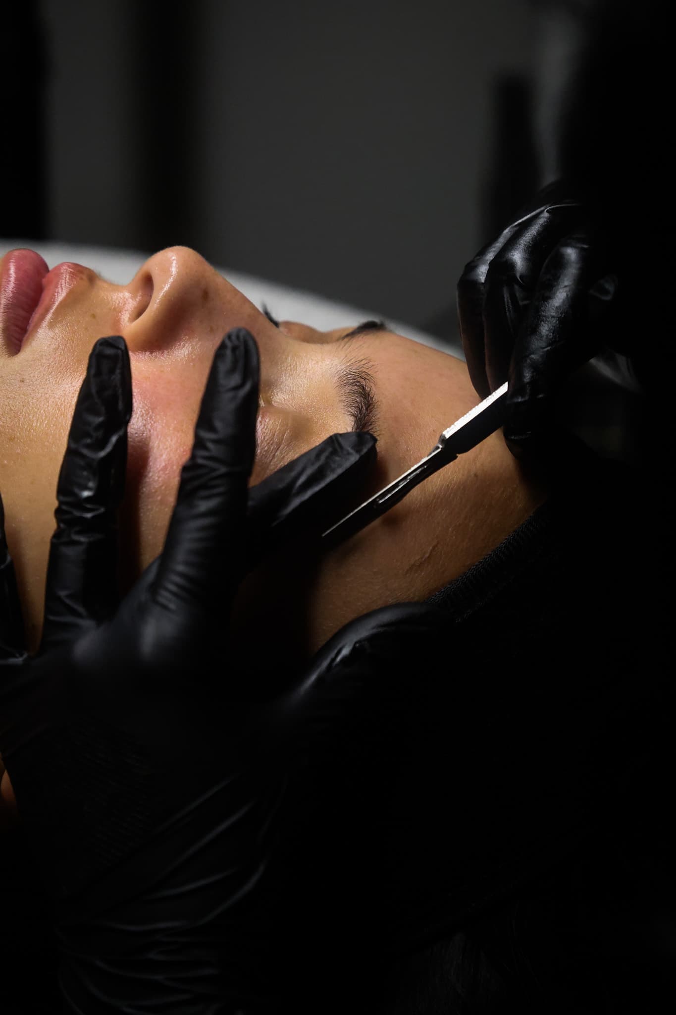 Esthetician performing dermaplaning on a client’s skin.
